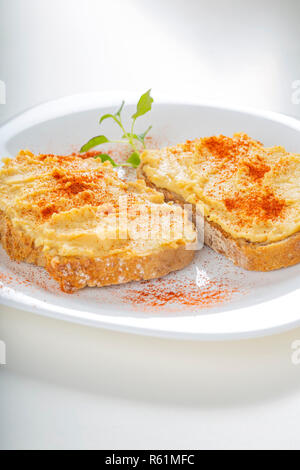 Two open sandwiches with hummus and paprika powder on a white plate Stock Photo