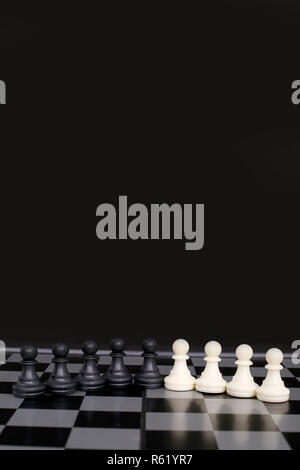 Picture of black and white chess pawns on the chessboard. isolated on the black background. Stock Photo