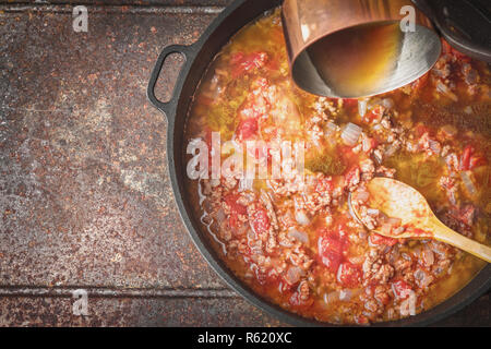 Adding chopped tomatoes on the pan with cooking paella top view Stock Photo