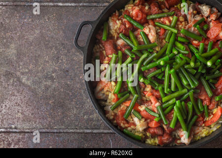 Adding chopped tomatoes on the pan with cooking paella top view Stock Photo