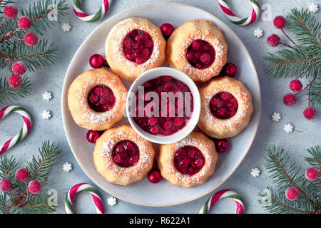 Mini bundt ring cakes with icing sugar on light background with fir twigs, berries and candy canes. Christmas holiday sweet food, flat lay with text s Stock Photo