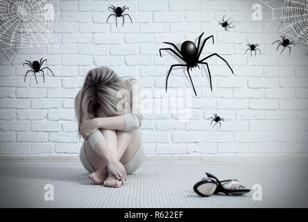 Woman sitting on the floor and looking on imaginary spider. Stock Photo