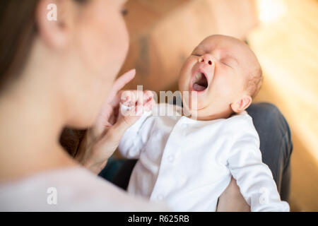Overhead View Of Mother Cuddling Yawning Newborn Baby Son At Home Stock Photo