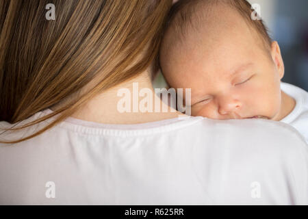 Loving Mother Cuddling Sleeping Newborn Baby Son Over Shoulder Stock Photo