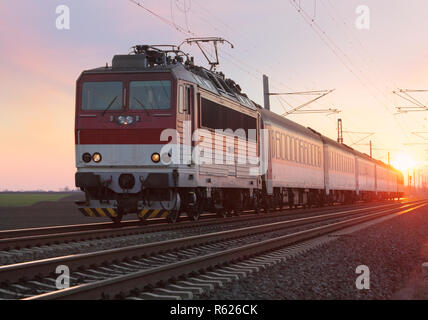 Passenger train on railway at sunset Stock Photo