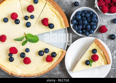 Classic sliced New York cheesecake with fresh berries and mint on stone background, top view. yummy breakfast Stock Photo