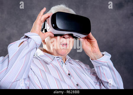 gray hairy elderly woman using virtual reality glasses Stock Photo