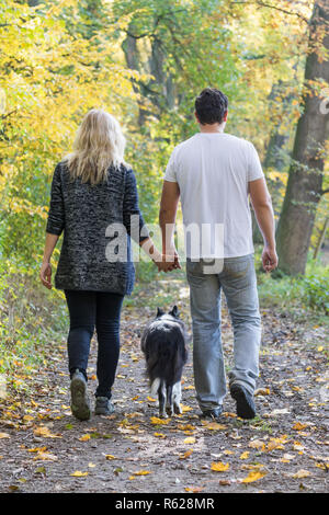 Young couple with a dog is on a walk in an autumn park Stock Photo
