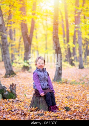 beautiful little girl stands on a trunk of tree smiling Stock Photo