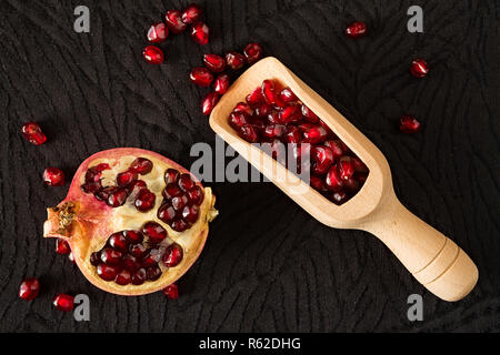 Closeup of half pomegranate fruit and bailer with seeds inside seen from above Stock Photo