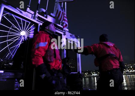 Boatswain’s Mate 3rd Class Ryan Bennett, a reservist with Coast Guard Station Washington, observes the bright lights of the Capital Wheel while on marine safety patrol near National Harbor, Maryland, Nov. 17, 2018. Reservists serve as a force multiplier in the Coast Guard’s efforts to protect our Nation’s Capital. Stock Photo