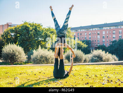 Beautiful couple practicing acro yoga in the morning on the grass lawn. Balance and healthy concept. Stock Photo
