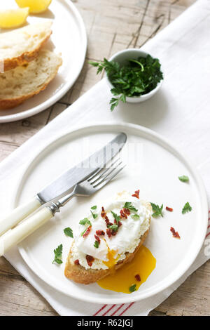 Crispy baguette toasts with cottage cheese, poached egg and dried tomatoes on a light background. Stock Photo