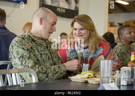 CAMP LEMONNIER, Djibouti – U.S. Representative Jenniffer Gonzalez-Colon from Puerto Rico, hands  Information Systems Technician Submarines 1st Class Matthew McNamara, a decorative coin at lunch with forward-deployed services members assigned to Camp Lemonnier, Djibouti during a visit on base, Nov. 21, 2018. The representatives are traveling to meet with national defense leaders to understand readiness and security in the area of responsibility.  CLDJ’s mission is to enable joint warfighters operating forward and to reinforce the U.S.-Djibouti relationships. Stock Photo