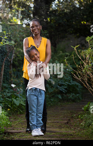 Granddaughter standing in front of grandmother in a garden Stock Photo