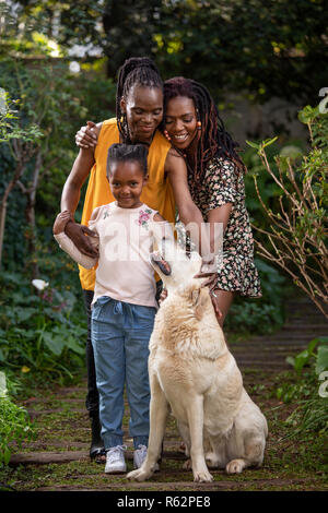 A family of women petting a dog Stock Photo
