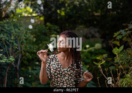 An African woman smelling a rose in a garden Stock Photo