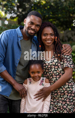A mother, father and daughter holding each other affectionately in a garden Stock Photo