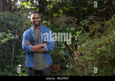 An African man standing in a garden, arms crossed Stock Photo