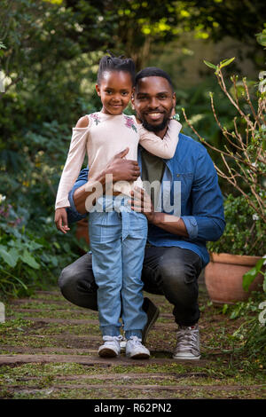 A man holding his daughter in a garden Stock Photo