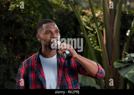 Closeup man drinking a beer in a garden Stock Photo