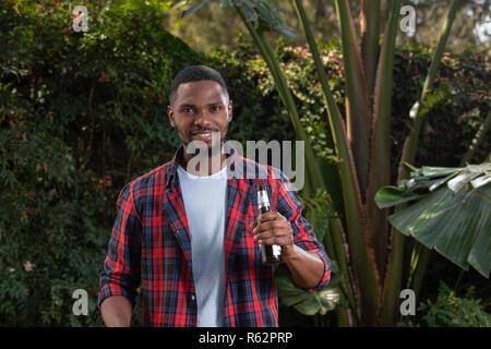 An African man holding a beer in a garden Stock Photo