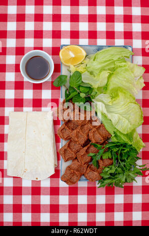 Traditional Turkish appetizer Cigkofte with lavash,  ingredients are raw meat,  bulgur ,onion, tomato paste, chili pepper and salt. Top view  on table Stock Photo