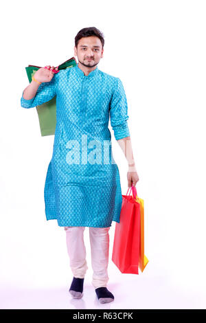 Indian man in ethnic wear with shopping bags, isolated over white background Stock Photo