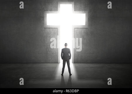 Business man standing in front of the shining cross Stock Photo