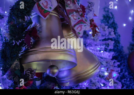 Christmas bell decorations hanging from a Christmas tree with Christmas lights in the background Stock Photo