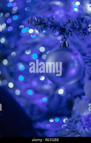 Silver Christmas bauble Hanging from a Christmas tree with Christmas lights in the Background Stock Photo