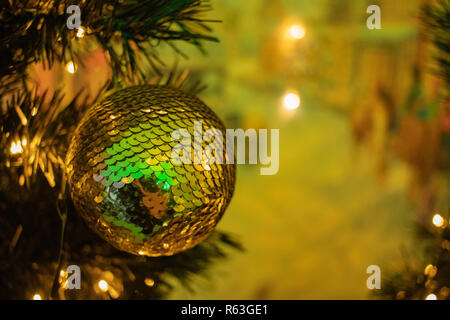 Golden bauble on a Christmas tree with Christmas lights in the background Stock Photo