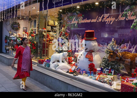 A woman walks past a shop in Mumbai, India, decorated for Christmas, the country's Christian minority's most important holiday Stock Photo