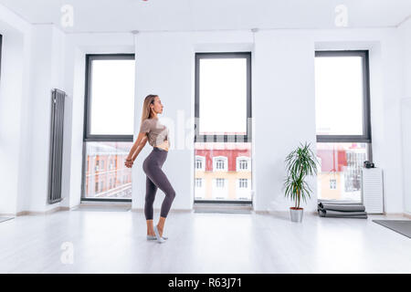 side view full length photo. oung sportswoman doing stretching exercise before dancin . copy space. begginer gymnast Stock Photo
