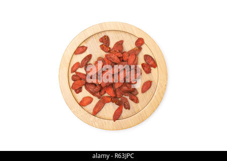 Lot of whole dried red goji berries on round bamboo plate flatlay isolated on white background Stock Photo