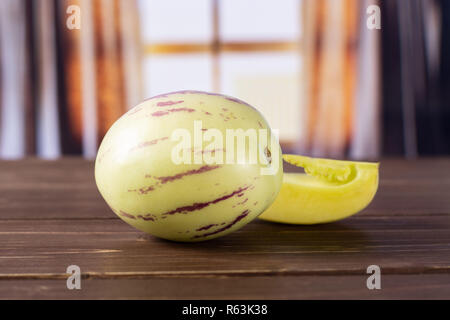 Group of one whole one slice of fresh striped pepino melon with silk curtains behind Stock Photo