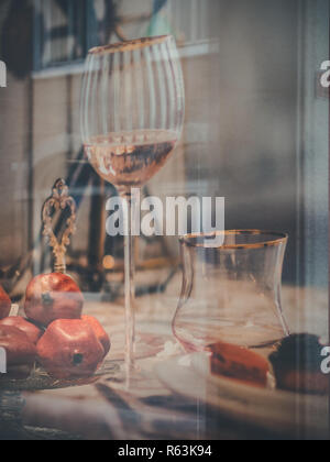 Rimini, italy, December 2018,Glasses and pomegranates show by a forniture showcase. Double exposure, Christmas atmosfere, Christmas mounting. Urban li Stock Photo