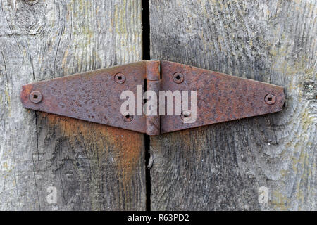 Close-up of a rusty metal hinge on weathered wooden garden gate Stock Photo