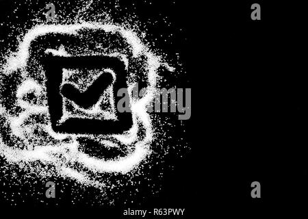Checking mark symbol in checkbox drawing by finger on white snow salt powder spot cloud in left side on black background. Tick concept with place for text. Copy space. Stock Photo