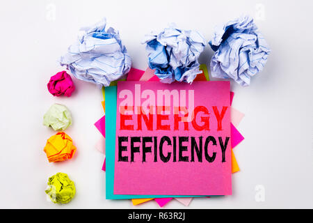 Writing text showing Energy Efficiency written on sticky note in office with screw paper balls. Business concept for Building Technology Efficiency on the white isolated background. Stock Photo