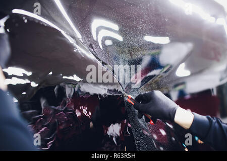 Applying tinting foil on car window in garage Stock Photo