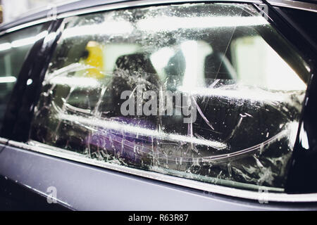 Applying tinting foil on car window in garage Stock Photo