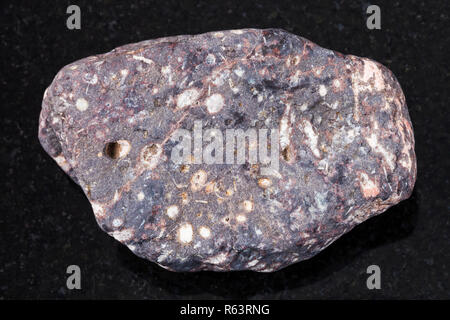 pebble of porous basalt stone on dark background Stock Photo