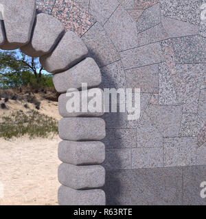 Upper right part of a cyclopean stone gate with granite tiled wall, sand and trees viewed through the opening. 3d render. Stock Photo