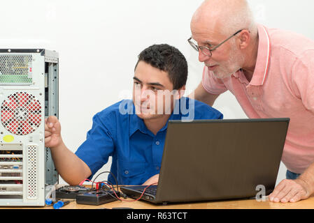 two technicians working on broken computer in workshop Stock Photo