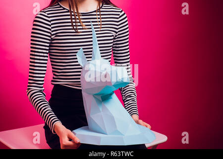 Fashion kid. Designer collection. White big unicorn origami made paper. Girl in beautiful pink dress. Studio shot. Stock Photo