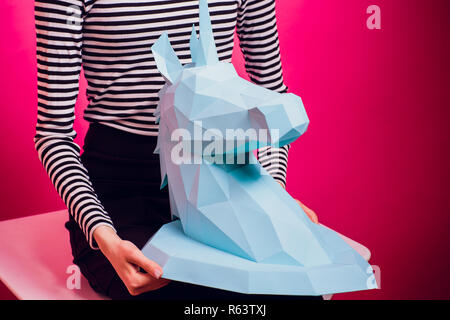 Fashion kid. Designer collection. White big unicorn origami made paper. Girl in beautiful pink dress. Studio shot. Stock Photo