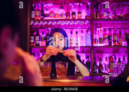 female bartender. girl with blue hair. cocktail making in night bar Stock Photo