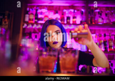 female bartender. girl with blue hair. cocktail making in night bar Stock Photo