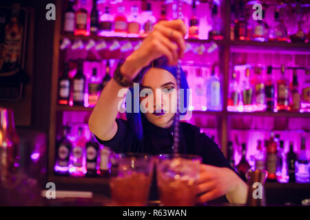 female bartender. girl with blue hair. cocktail making in night bar Stock Photo